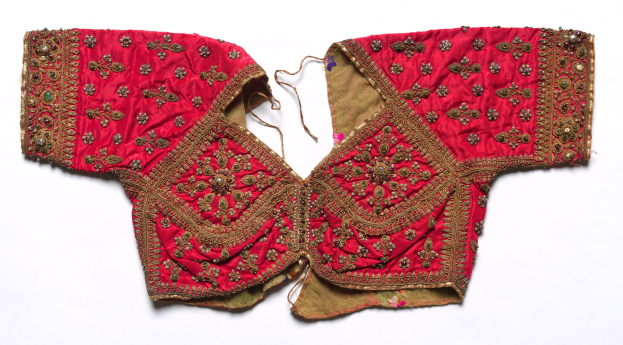 Ein rotes Oberteil mit goldener Stickerei mit aufwändigen Designs, vor einem weißen Hintergrund.