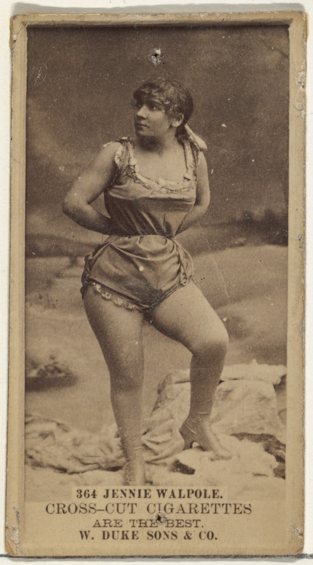 Ein Schwarz-Weiß-Foto einer älteren Frau in einem vintage-Badeanzug, die selbstbewusst auf einem Strand steht, mit einem Dutt und geschlossenen Augen in einem friedlichen Ausdruck.