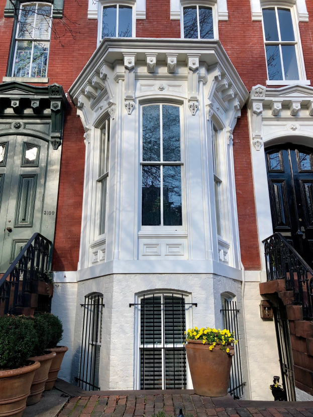 Eine Reihe von Stadthäusern in Washington, DC, mit Fenstern, Türen, Geländern, Treppen, Blumentöpfen und einem Weg, der zu ihnen führt.