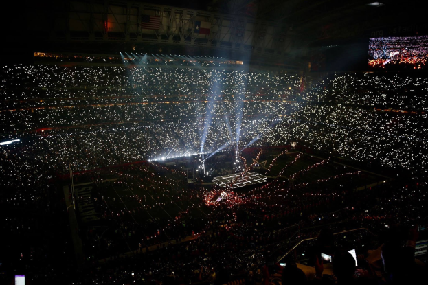 Gro├čes Publikum in einem hell erleuchteten Stadion bei Nacht mit einem Bildschirm auf der rechten Seite, der die Ergebnisse der Super Bowl XLVII-Halbzeitenshow anzeigt.