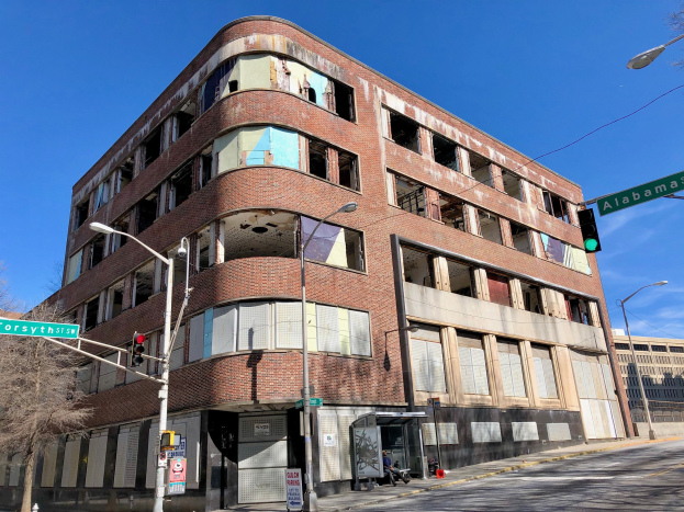 Altes Backsteingebäude an einer Straßenecke mit einer Tafel, die darauf hinweist, dass es formerly der Hauptsitz der University of Illinois at Chicago war, umgeben von Straßeninfrastruktur und Fahrzeugen.