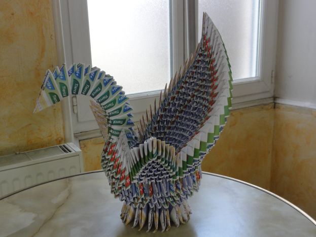 Origami-Pavian aus Toilettenpapier, auf einem Tisch vor einer Wand mit einem Fenster aufgestellt.