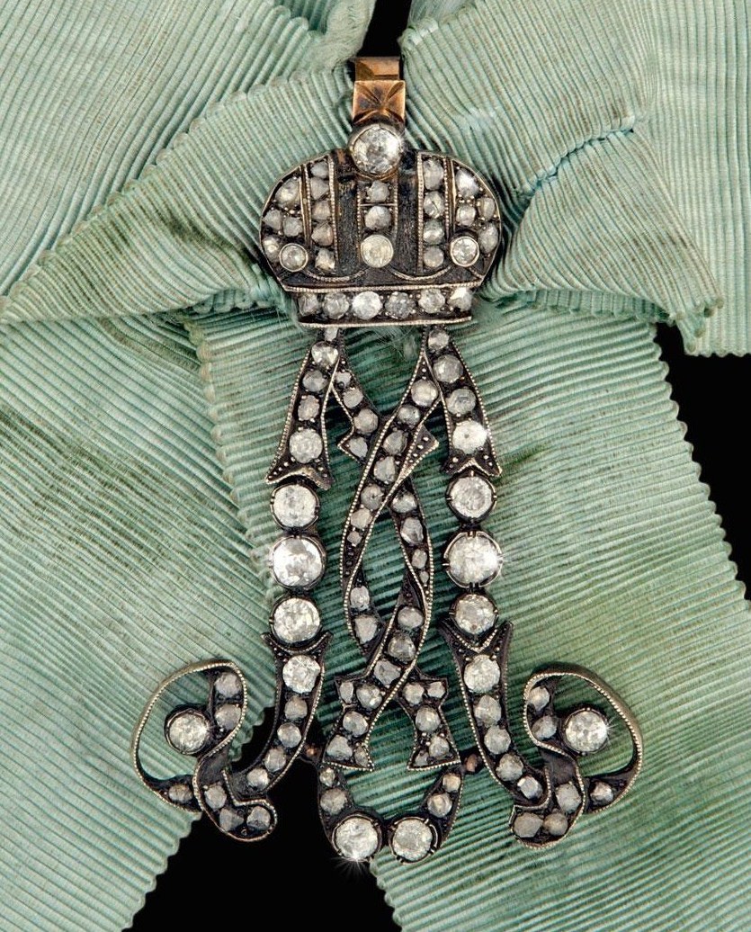 Gold- und Diamantanhänger mit einer Krone auf einem grünen Stoffhintergrund.