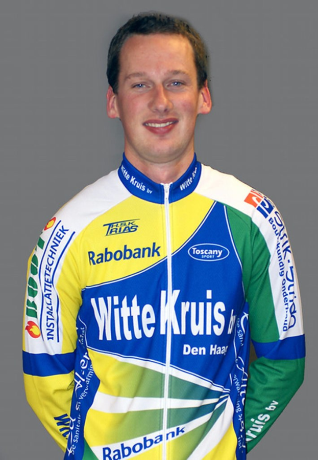 Ein männlicher Sportler posiert für ein Foto und trägt ein Shirt mit mehreren Sponsorenlogos.