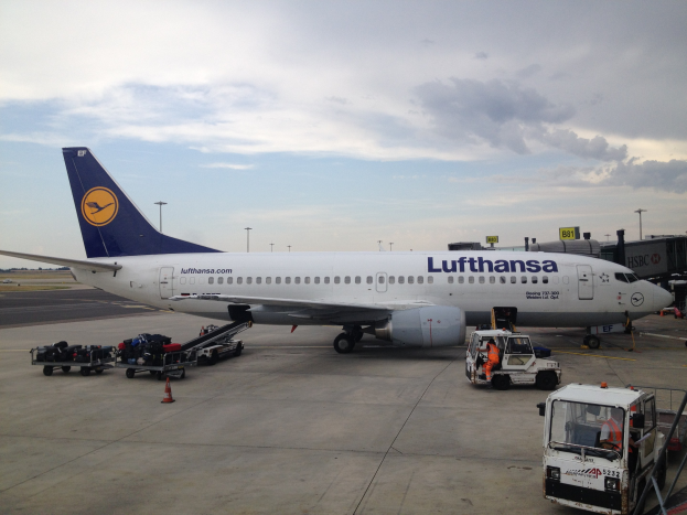 Lufthansa Airbus A320-200 auf dem Frankfurt Airport geparkt mit Bodenbetriebsfahrzeugen, Verkehrsinseln und Informationsschildern unter einem bewölkten Himmel.