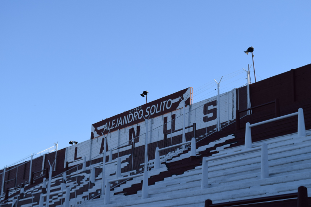 Fußballstadion mit Treppen, Geländern, Laternen und einem Schild unter einem sichtbaren Himmel.