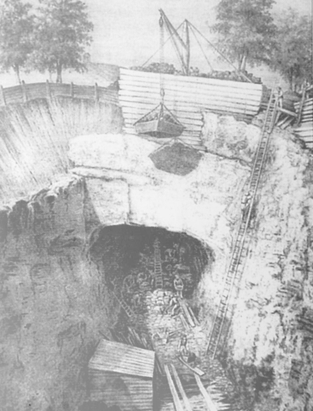 Schwarzes und weißes Foto eines Tunnels mit einem Kran im Inneren, umgeben von Bäumen und Himmel, mit Menschen und Leitern am Boden, die auf einen Kohlebergbau hinweisen.