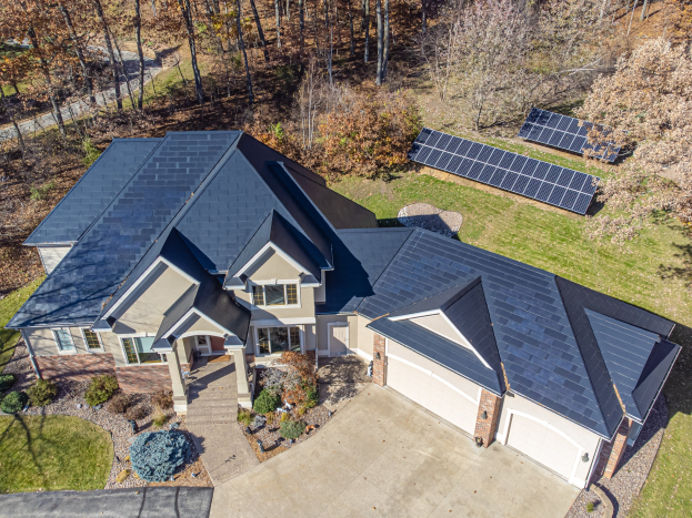 Luftaufnahme eines Hauses in North Carolina mit Solarmodulen auf dem Dach, umgeben von grünem Gras, Pflanzen und Bäumen.