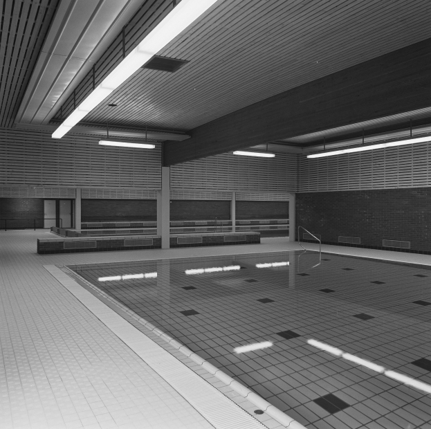 Indoor-Schwimmbad mit klarem Wasser, gefliestem Boden und Wänden, Deckenbeleuchtung und wenigen umgebenen Gegenständen in einer ruhigen Umgebung.