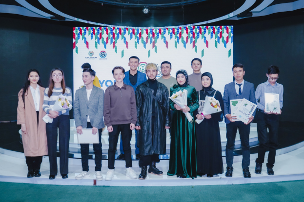 Gruppe von Menschen auf einer Bühne mit Blumensträußen und Urkunden vor dem Hintergrund "Youth Solar Awards 2019".