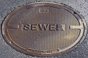 Metall-Schachtreihe auf der Straße mit der eingravierten Aufschrift "Kanal"