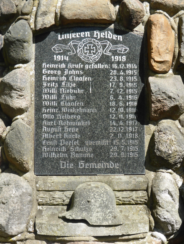 Steinwand mit einer Plakette und einem Helm darauf, wahrscheinlich ein Denkmal für deutsche Weltkriegsmilitärangehörige.