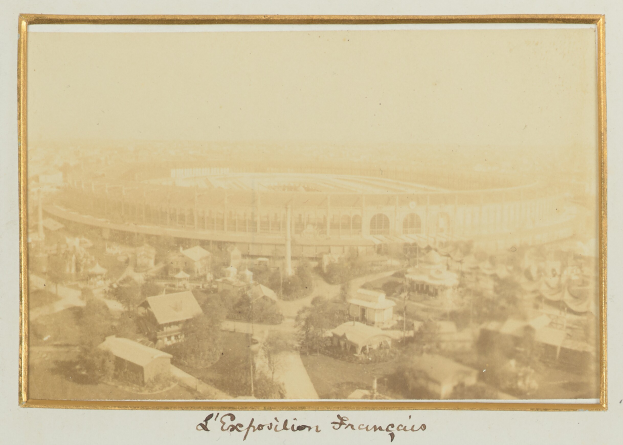 Altes Schwarz-Weiß-Foto eines Stadions, umgeben von mehrstöckigen Gebäuden, Bäumen und Strommasten mit Text am unteren Rand.