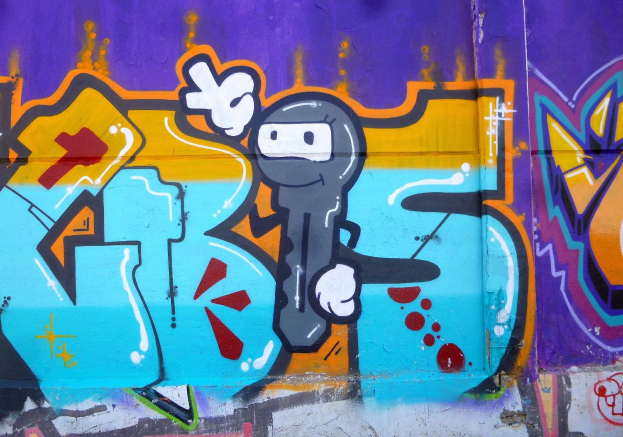 Eine Wand voller bunter, farbenfroher Graffiti mit einem hellen Cartoon-Charakter in verschiedenen Größen und Formen.