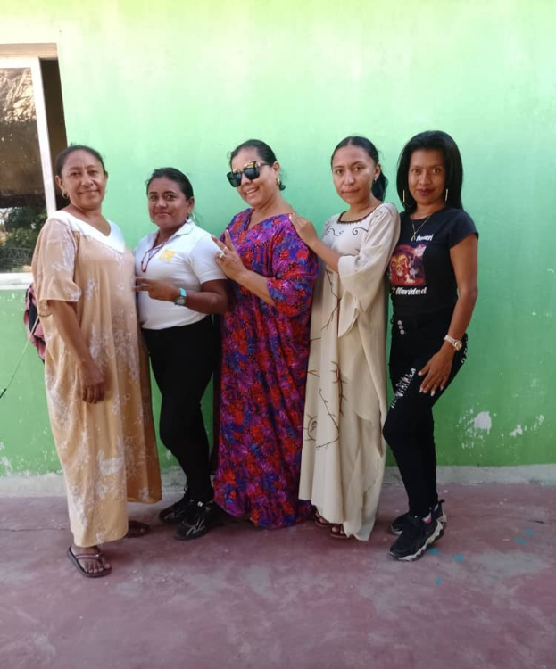 Frauen-Gruppe vor einer grünen Wand mit einem Fenster auf der linken Seite, die an einem Internationalen Frauentag-Event teilnimmt.