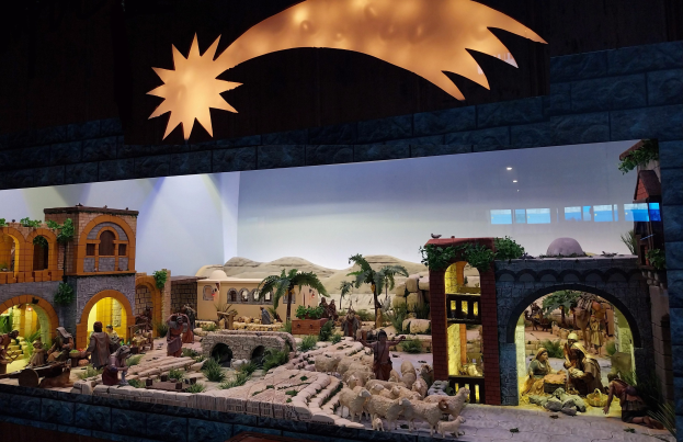 Eine Krippe in einem Museum mit Figuren, Tieren und Szenerie, beleuchtet von einer Deckenbeleuchtung an der Wand.