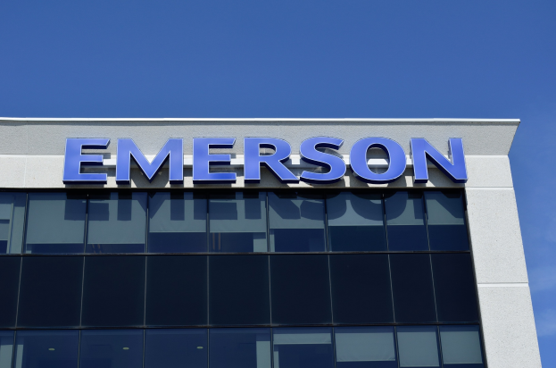 Emerson-Logo auf einem Gebäude mit der Aufschrift "Emerson investiert 1,5 Milliarden US-Dollar in den USA" vor einem klaren blauen Himmel.